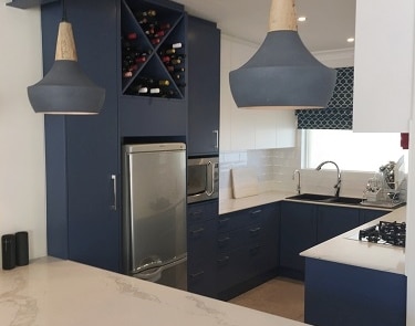 Blue cabinetry kitchen with wine storage and quartz waterfall countertop.