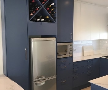 Built-in wine rack and appliance cabinetry with navy blue finishes.
