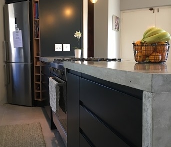 Dark modern kitchen island with concrete countertop and integrated gas hob.