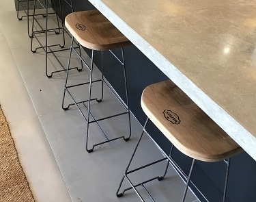 Breakfast bar seating beneath a concrete countertop with integrated gas hob.