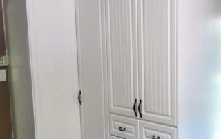 A tall, white cabinet with multiple drawers and doors, featuring a textured design on the front.