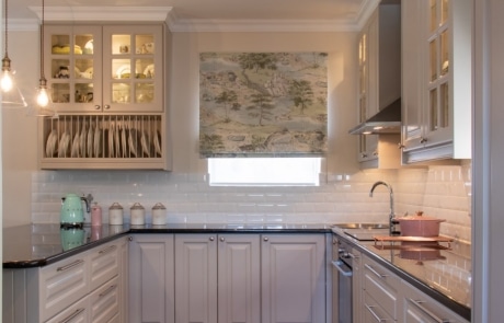 A modern kitchen featuring white cabinetry, a black countertop and wooden flooring.