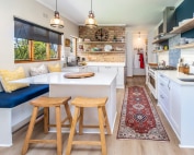 Bright farmhouse kitchen with island seating and exposed brick feature.