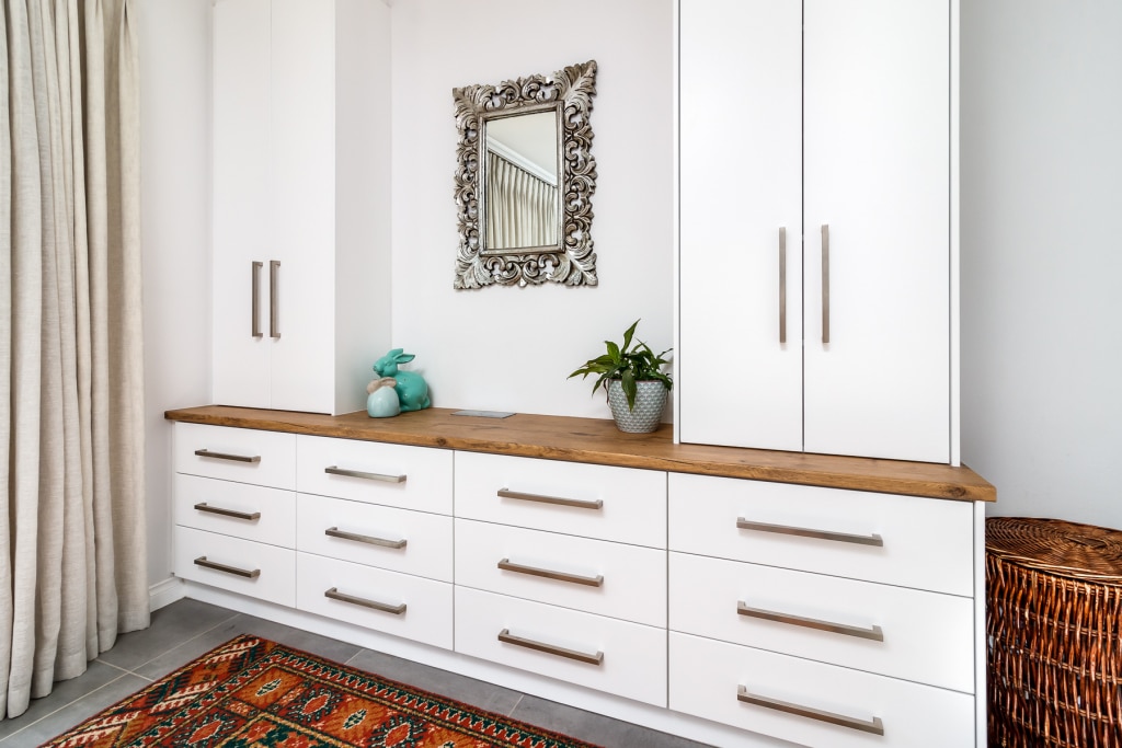A modern interior with a white cabinet featuring drawers and a wooden countertop complimented by a patterned rug