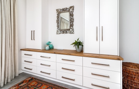 A modern interior with a white cabinet featuring drawers and a wooden countertop complimented by a patterned rug