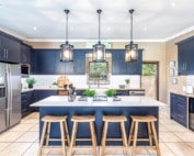 Classic navy kitchen with large island seating, subway tiles, and statement pendant lighting.