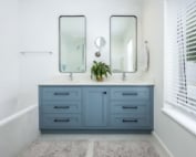 Blue-grey double vanity with twin mirrors and integrated sinks.