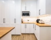 White shaker-style cabinetry with timber countertops and subway tiles.