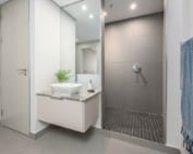 Floating vanity with stone countertop and walk-in tiled shower.