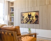 A stylish living room featuring a wooden accent wall with a mounted TV displaying a scene of black cats playing musical instruments.